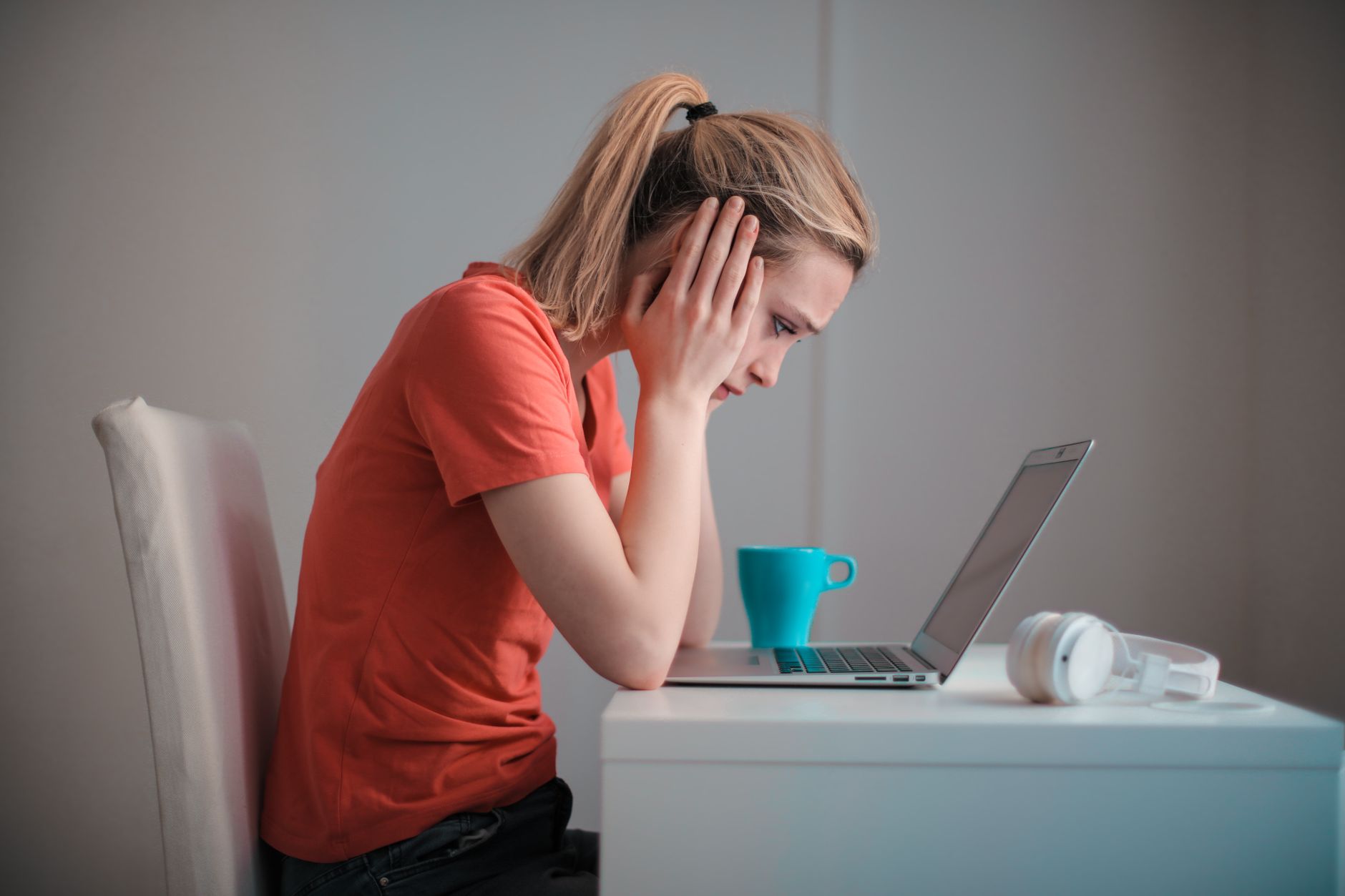 a person closing a laptop with a worried expression at a home desk