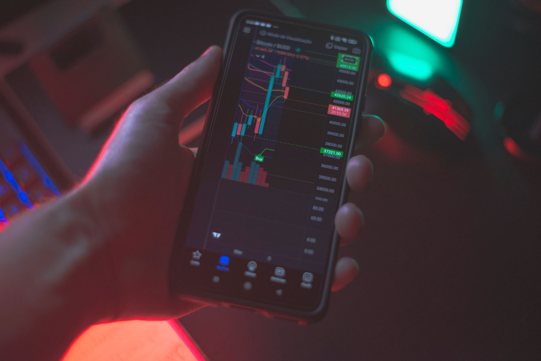 a hand holding a smartphone displaying a cryptocurrency transaction screen at a desk