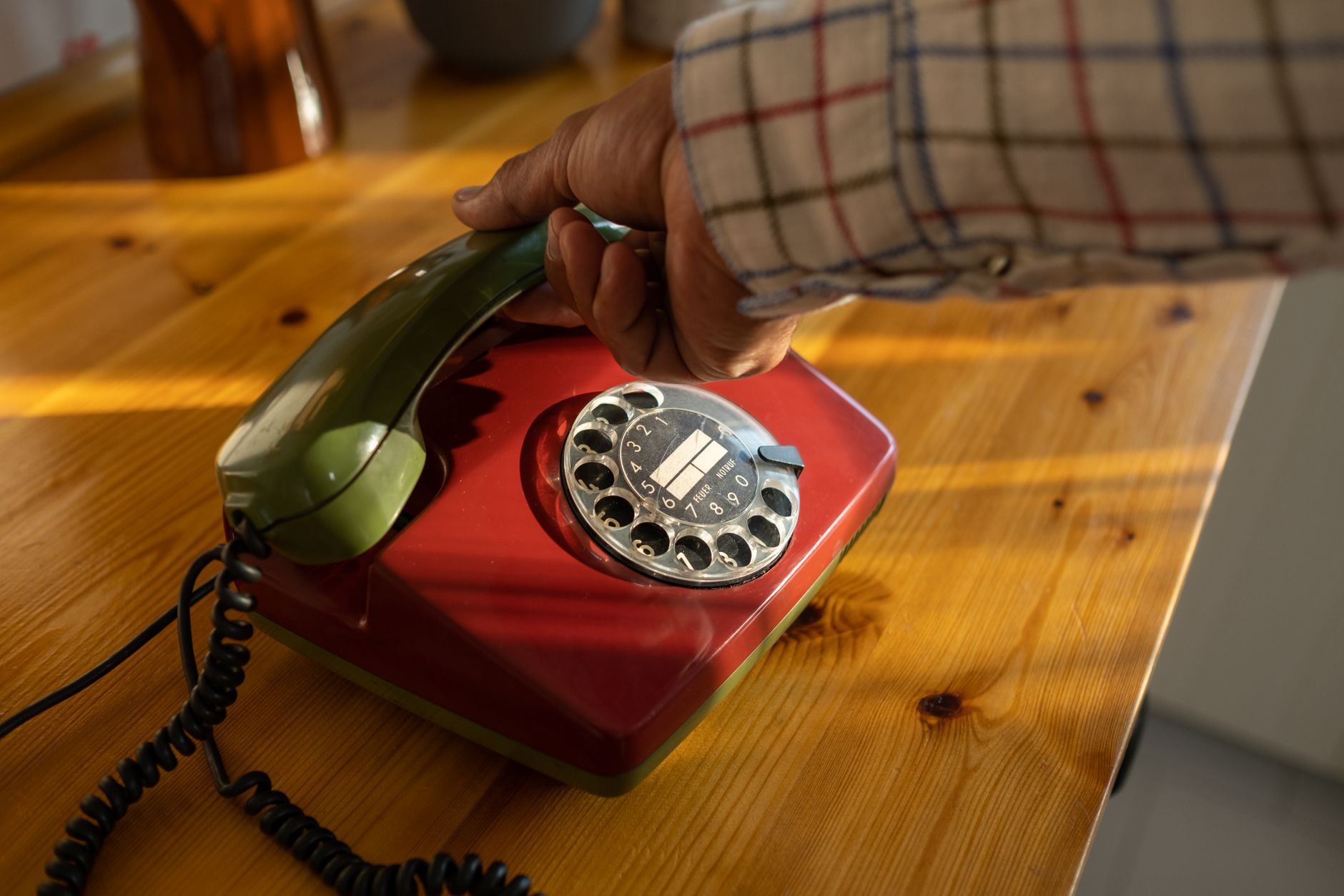 A senior man talking on a landline phone with a call blocker device on the table